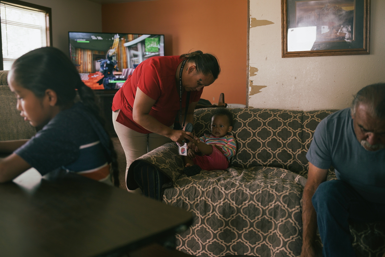 Desirae puts shoes on LaRose Leigh as her father and one of her brothers get ready to leave the house too. Desirae is happy to be raising her daughter back on the reservation, connected to family and her native heritage. She speaks to LaRose Leigh in both English and Arapaho.