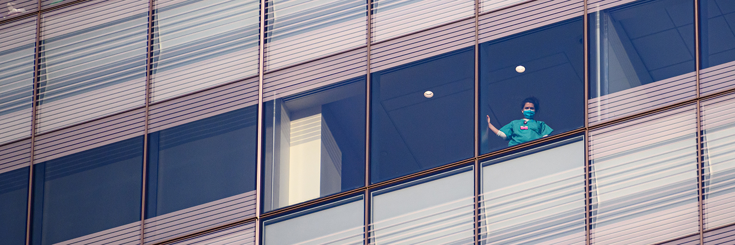 A medical worker watches from the window at NYU Langone Health hospital as people applaud to show their gratitude to medical staff and essential workers on the front lines of the coronavirus pandemic on May 10, 2020 in New York City.