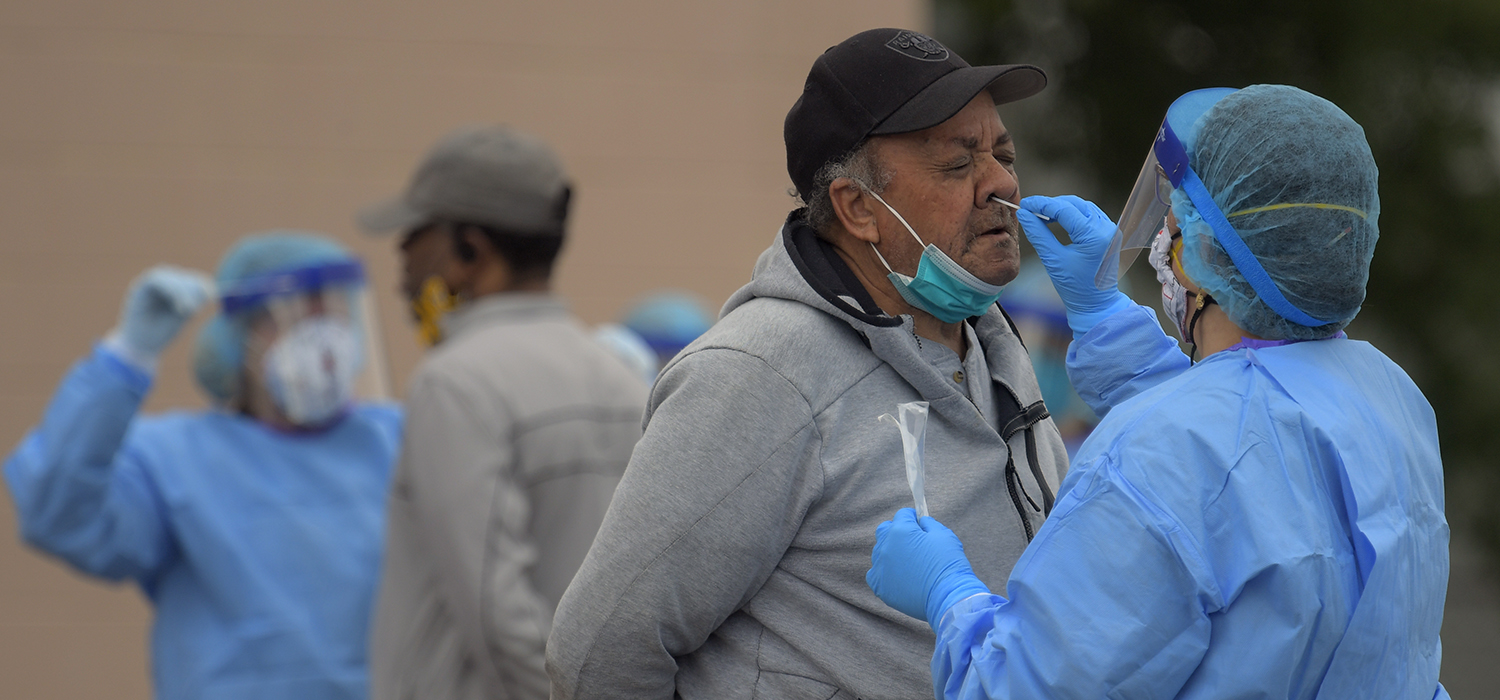 A health volunteer, right, uses a swab to collect a sample from the nose of 70 year old Richmond area resident Wayne Thorpe. This is part of the testing for covid-19 in a shopping center that services an area that has public housing in Richmond, VA.