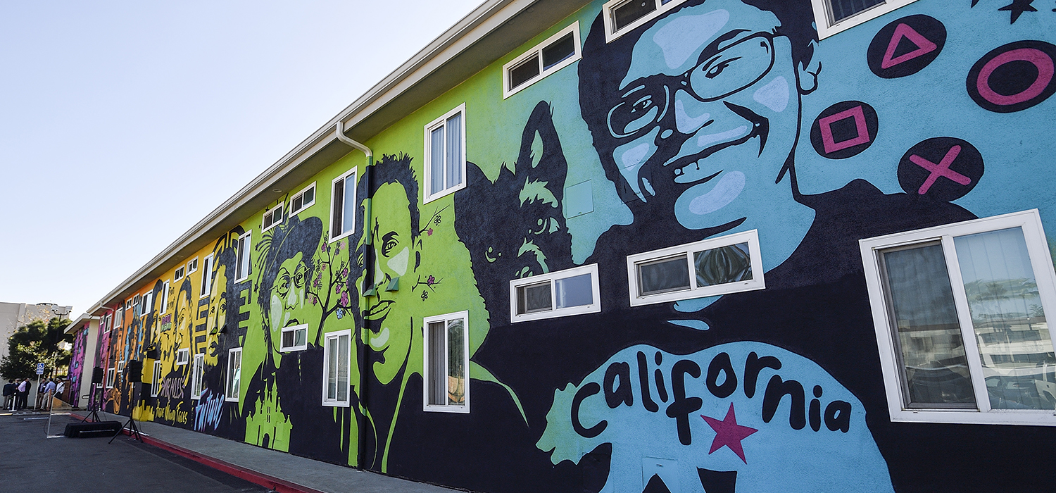 A mural features faces and quotes from residents of permanent supportive housing