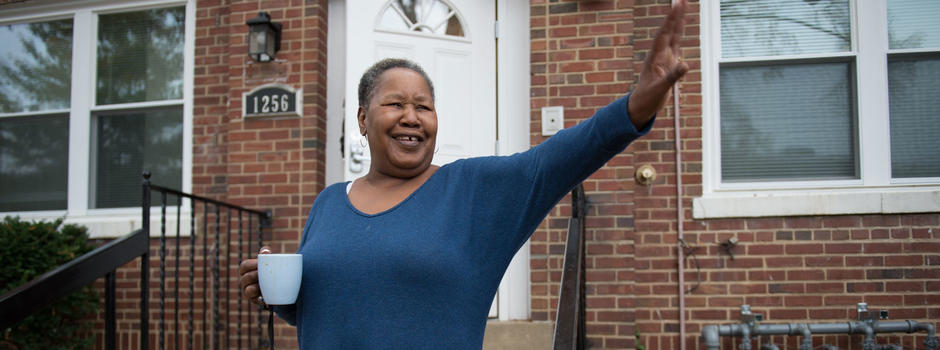 Woman waving in front of house