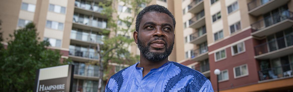 photo of African American man standing with housing in background