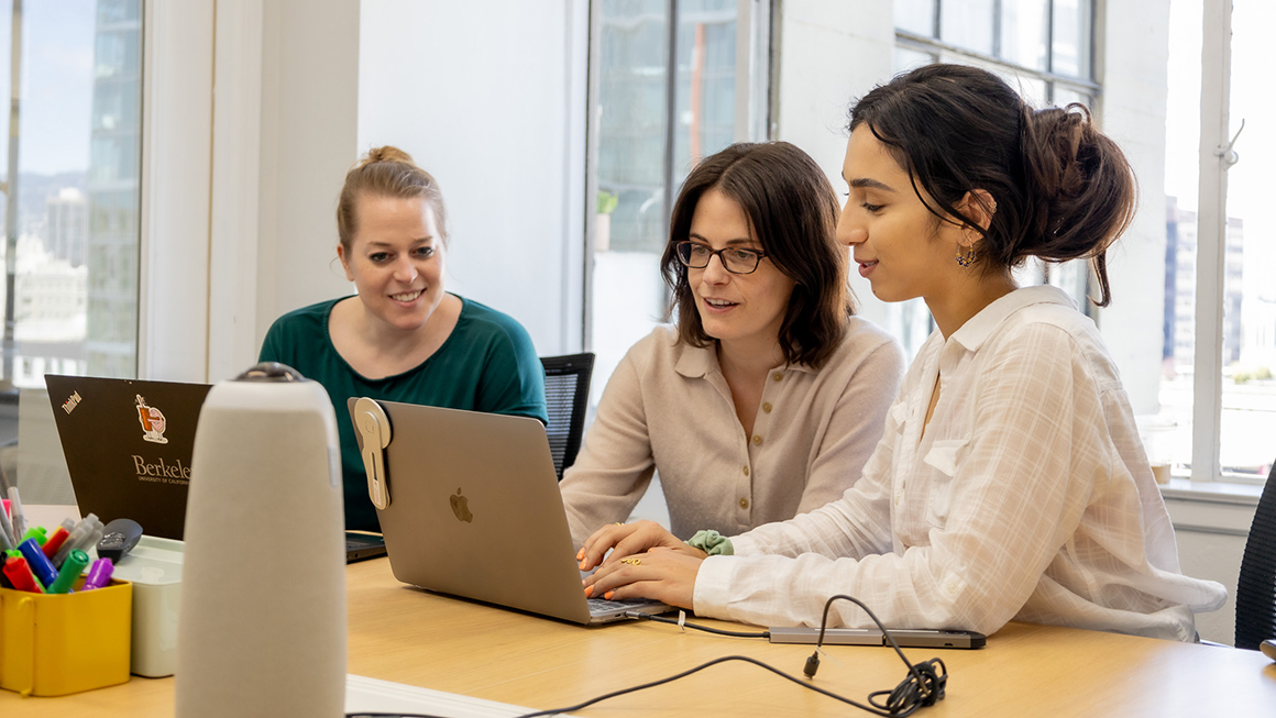 photo of people sitting together looking at laptop