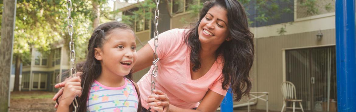 photo of mother pushing child on swing