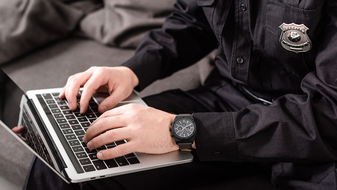 photo of cropped view of policeman typing on laptop keyboard