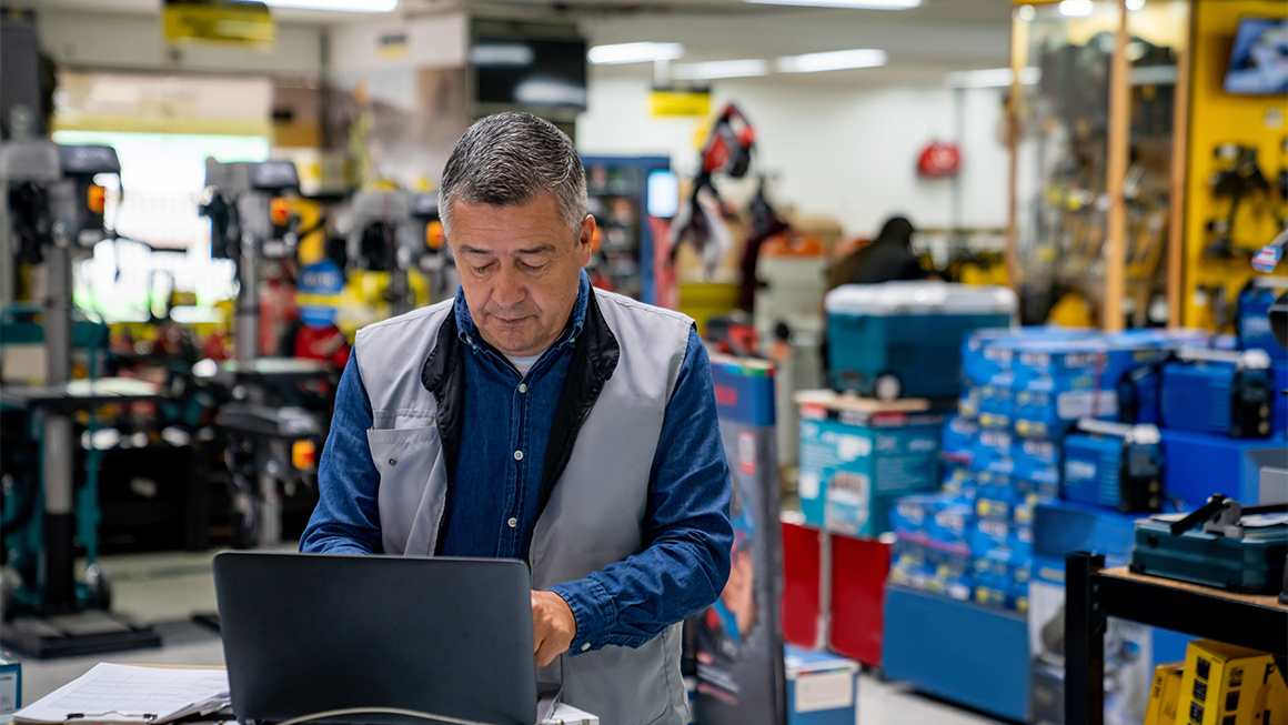 An older man checks his laptop at work.