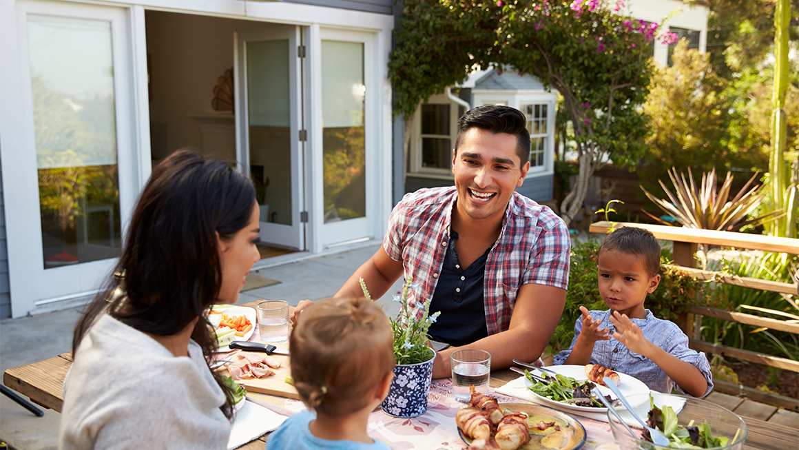 Family of four eating a meal outside at a table