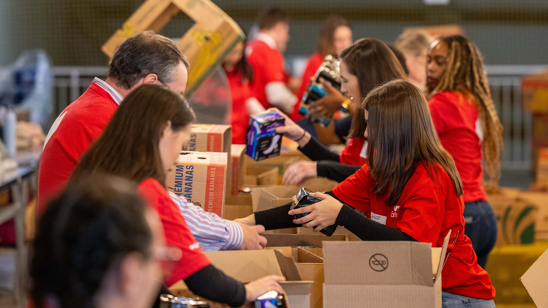 A group of volunteers prepares care packages at a food bank. 