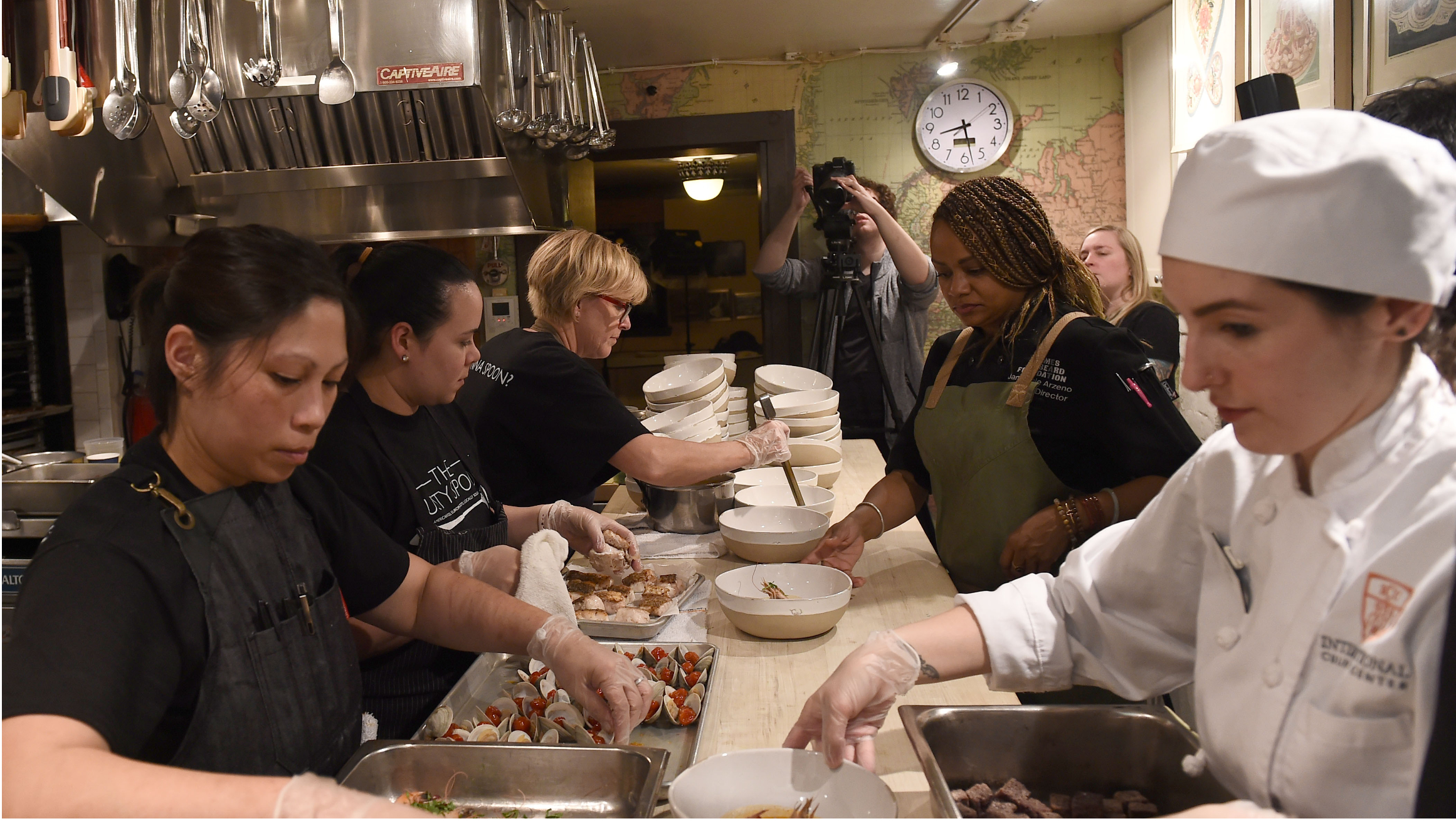 Restaurant workers gather around a table and plate food