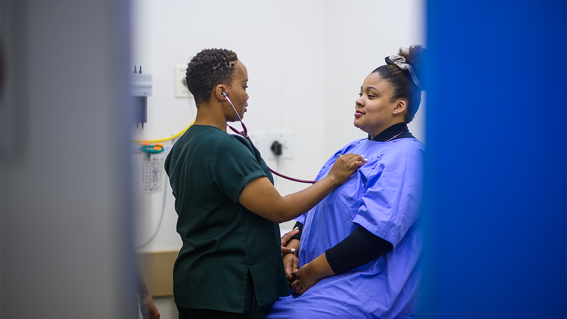 A doctor holds a stethoscope to her patient's chest