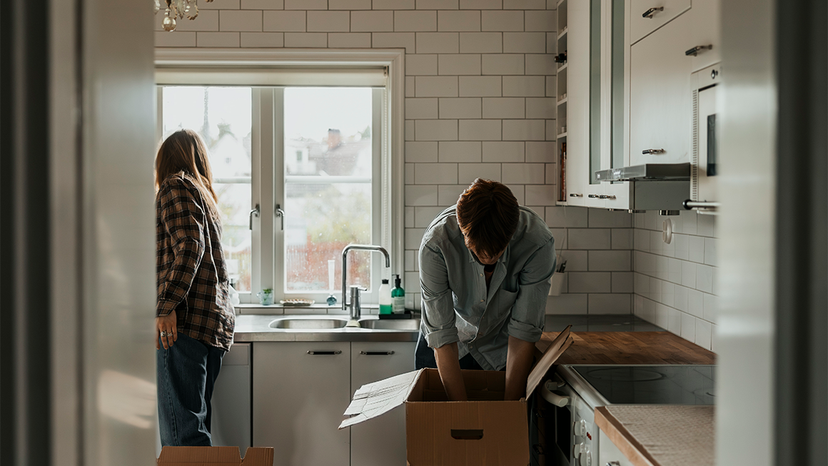 A couple unpacks boxes in a kitchen
