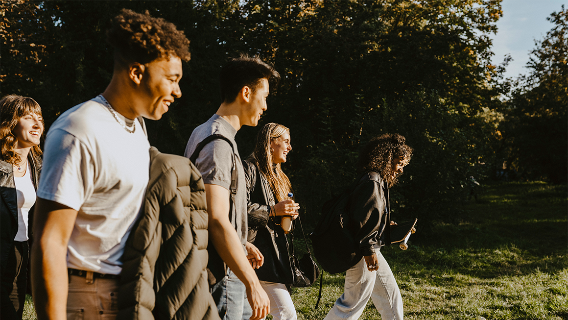 photo of happy male and female friends walking on road in park