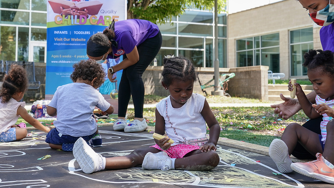 Four toddlers play with chalk outside