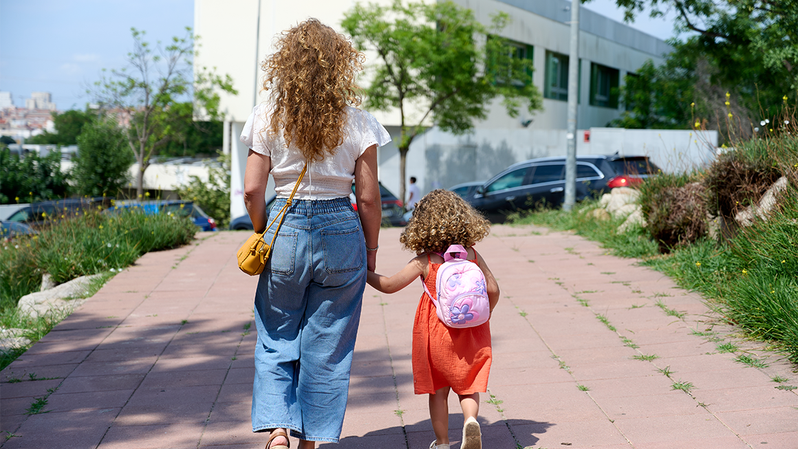 Photo of a mother walking her daughter to school on a sunny day. 