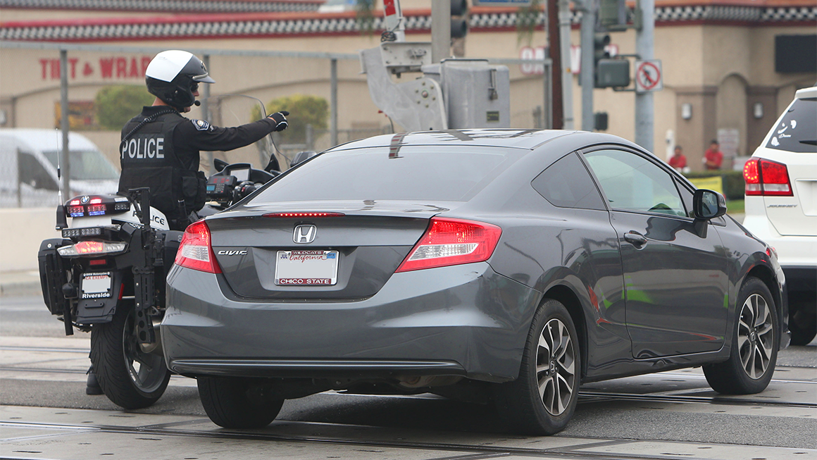 Police officer on a motorcycle pulls over a car