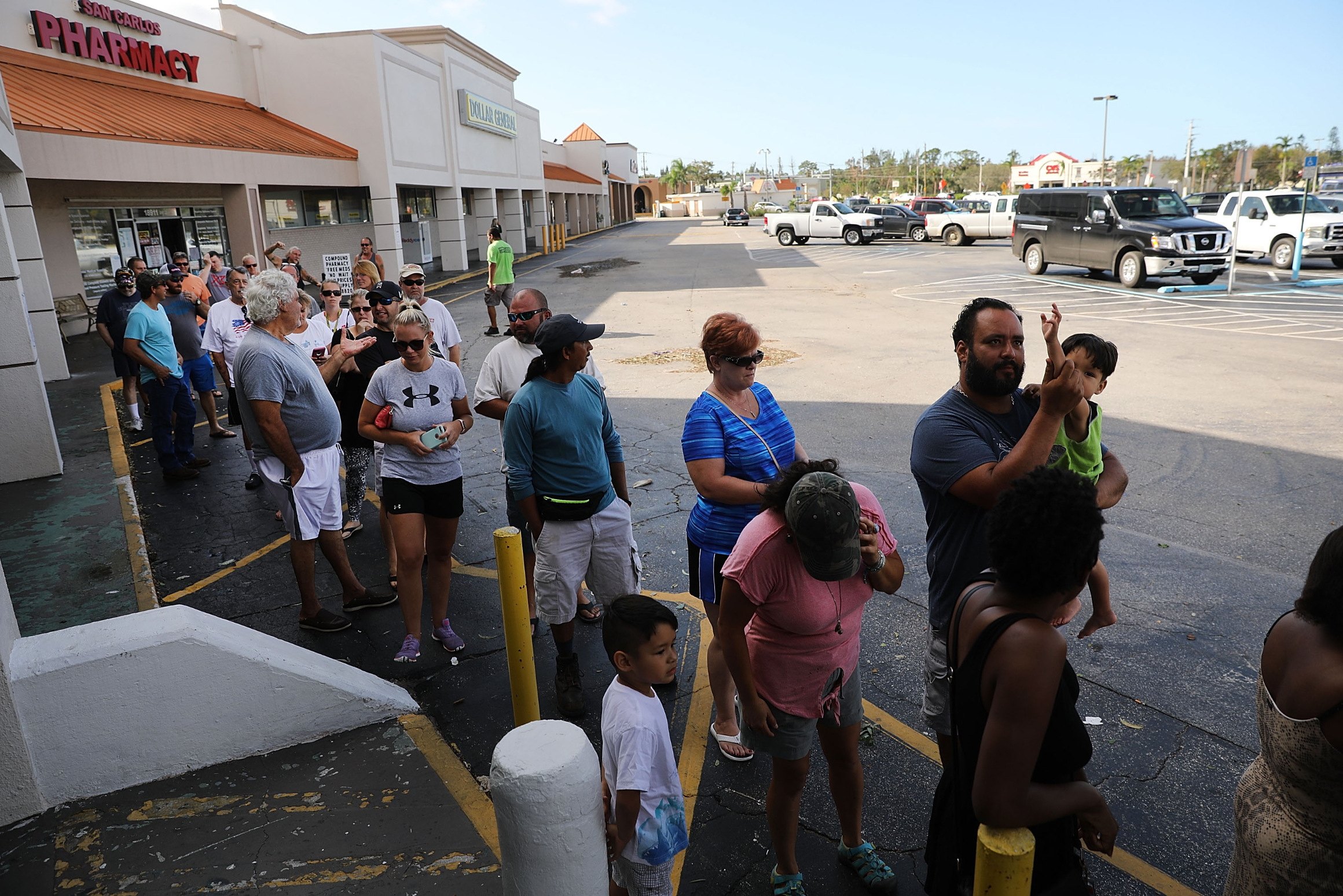 People wait in line outside a strip mall pharmacy.