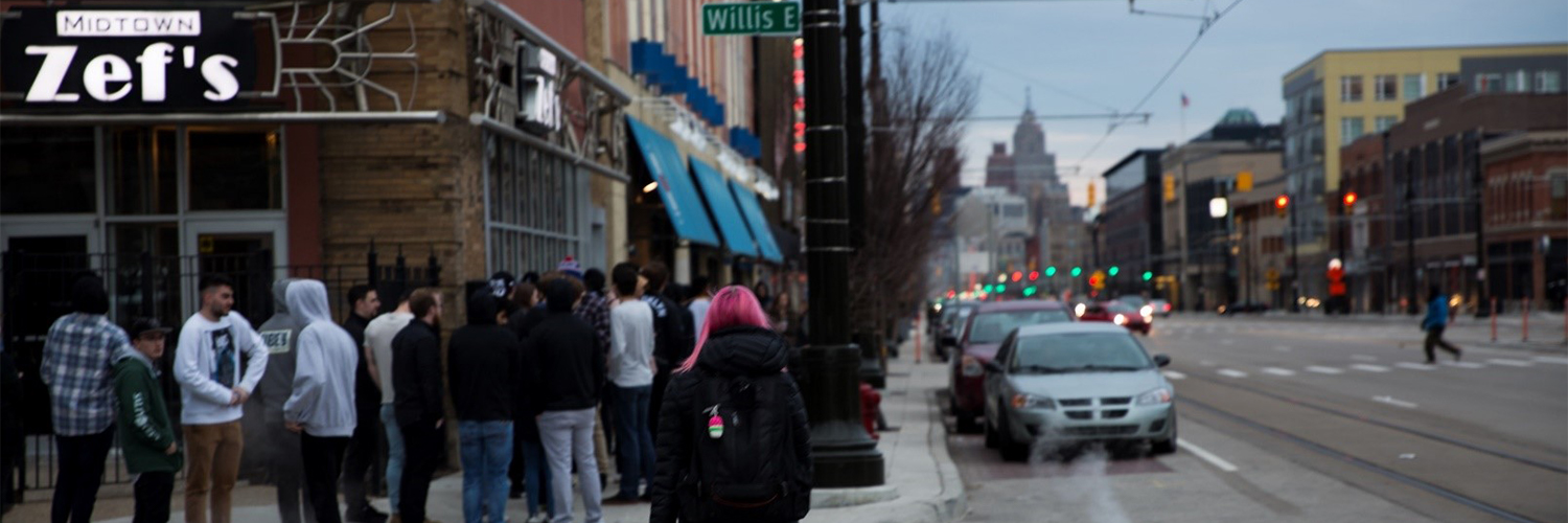 girl walking towards a crowd outside of a restaurant
