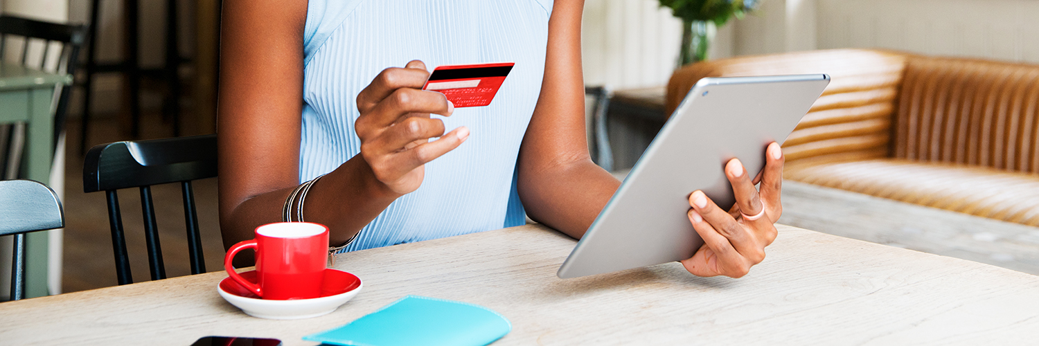 Person looks at credit card and tablet