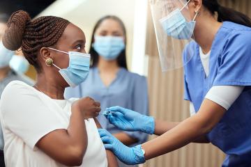Young woman getting her covid vaccination from a female nurse in the office.