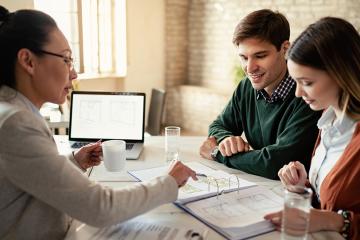 Smiling couple and insurance agent going through real estate plans during a meeting in the office.