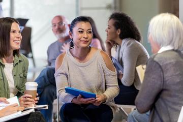 Small group members smile as mature adult female leader speak