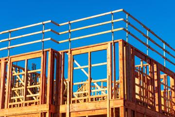 New residential wood framed building construction under blue sky.