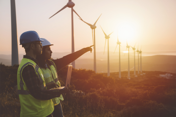 photo of workers standing in front of wind turbines