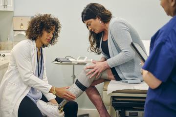 photo of doctor with her amputee patient, adjusting the patient’s prosthetic limb