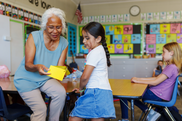 photo of teacher helping elementary age student during class