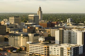 A high shot of an urban area with many different kinds of buildings, including a tall tower, apartments, and a parking garage.