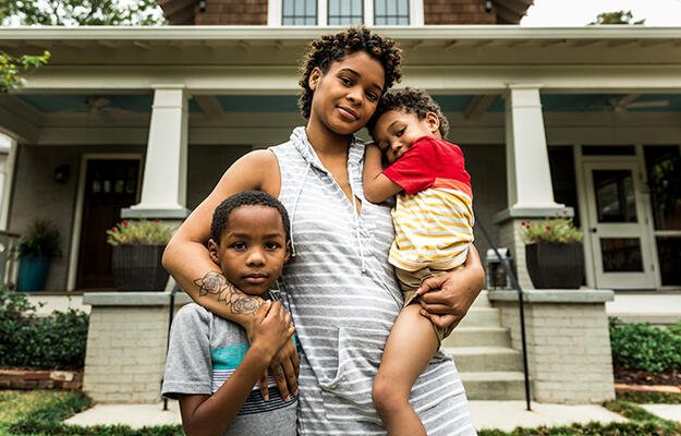 Family stands in front of house