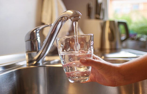 Person filling glass from faucet