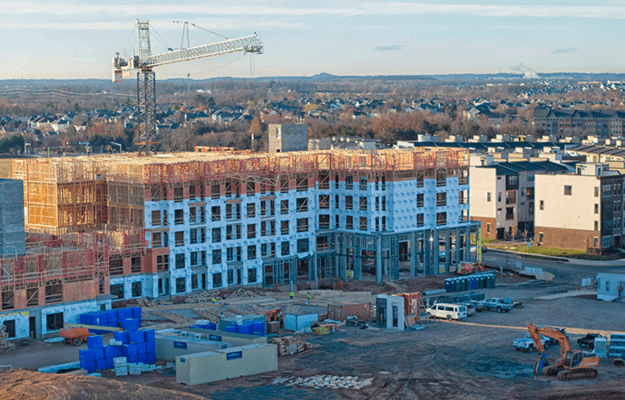 An aerial view of a large building under constriction in front of a gravel construciton site