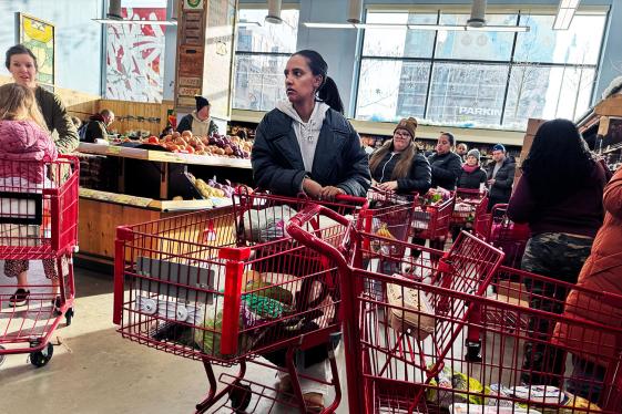 People waiting in line to check out at a grocery store.