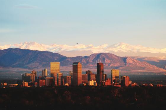 The Denver city skyline silhouetted against the Rocky Mountains.