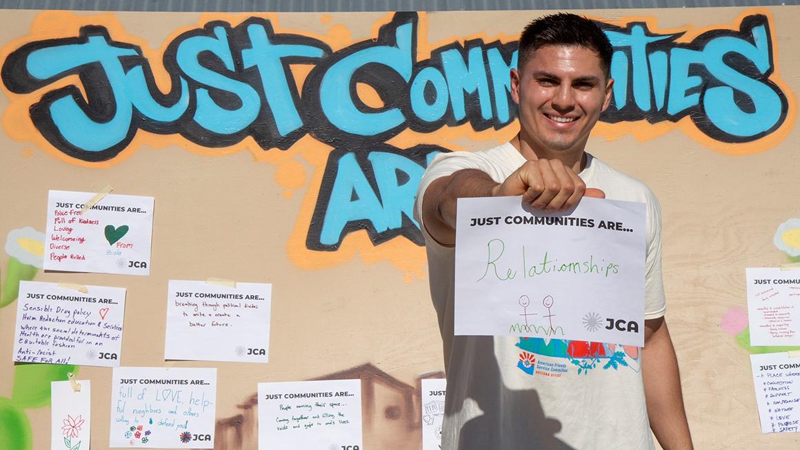 Man proudly holding banner that says "Just communities are relationship."