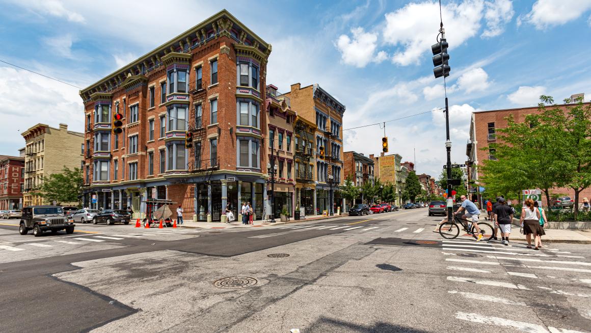 photo of  pedestrians walking around the intersection of 12th and Vine Streets in the rapidly gentrifying Over-the-Rhine district on a summer day