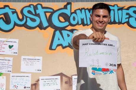 Man proudly holding banner that says "Just communities are relationship."