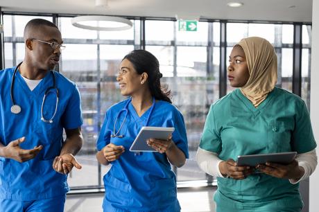 Three nurses walking down a hallway. 