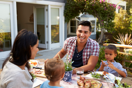 Family of four eating a meal outside at a table