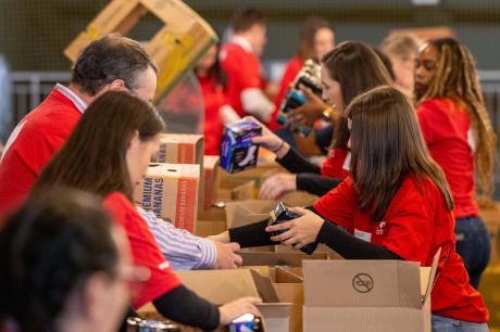 A group of volunteers prepares care packages at a food bank. 