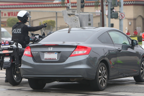 Police officer on a motorcycle pulls over a car