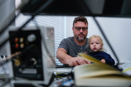 A man holds a child on his lap while he uses a computer