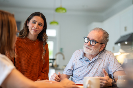 Photo of a young adult talking with her parents in their kitchen.