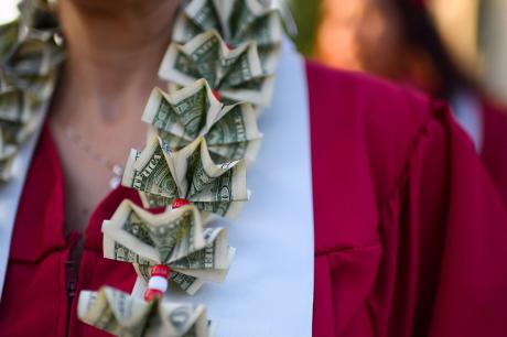 A graduate wears a lei made of dollars