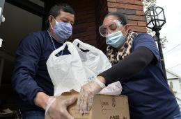 Jessica Armijo distributes food and packages of donated goods to people in need outside the Pan Y Cafe in Chelsea, Massachusetts on April 14, 2020. 