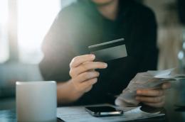 A person pays bills and holds a credit card
