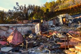 A scene of extensive destruction showing the charred remains and rubble of a building that has been severely damaged by fire.