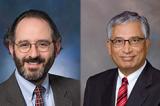 A photo of two individuals. Both are smiling, have suits, ties, and glasses.