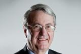 A photo of Pinto. White hair, glasses, slight smile, suit.